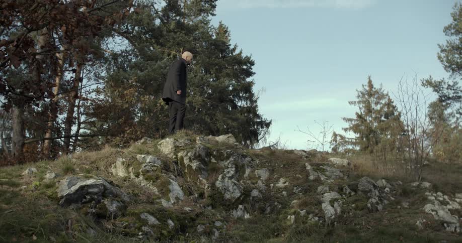 A man climbs a small hill in the forest