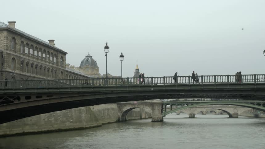 People walk across a bridge on a cloudy day