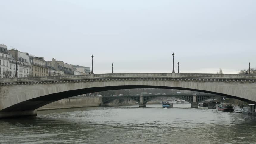 A pedestrian walks over a canal bridge on an overcast day