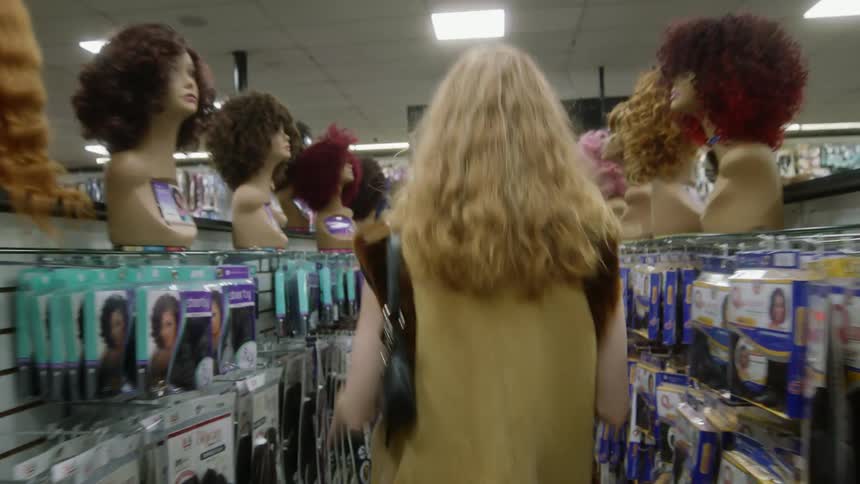 A young woman is walking inside of a store in the day time