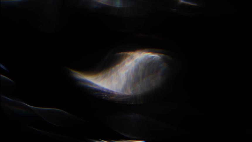 Close up of light being distorted reflecting on glass against a dark background