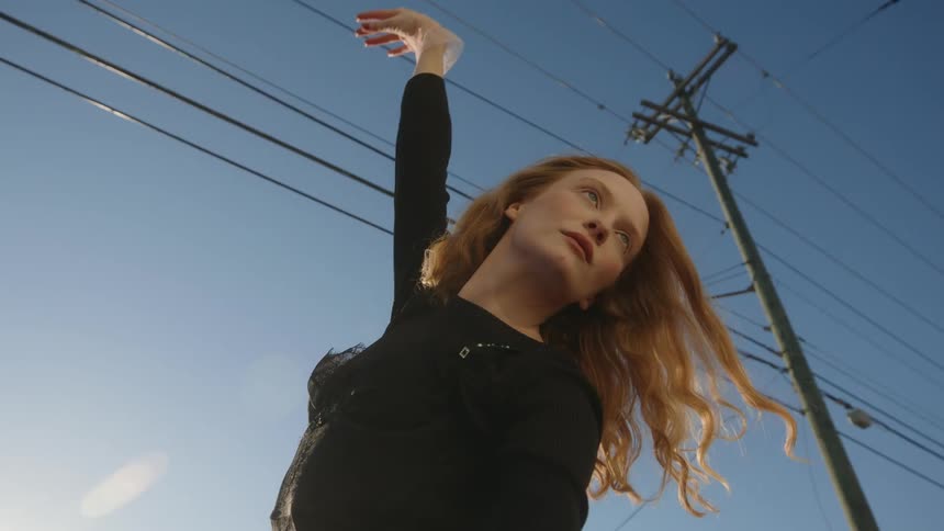 A woman is dancing outdoors during the daytime