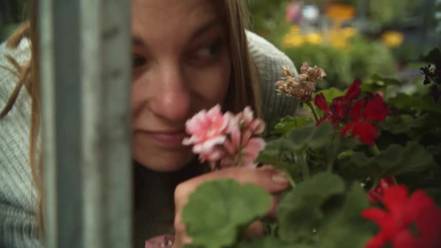 Mother and daughter smelling flower on the outdor shelfs of a store in a small town