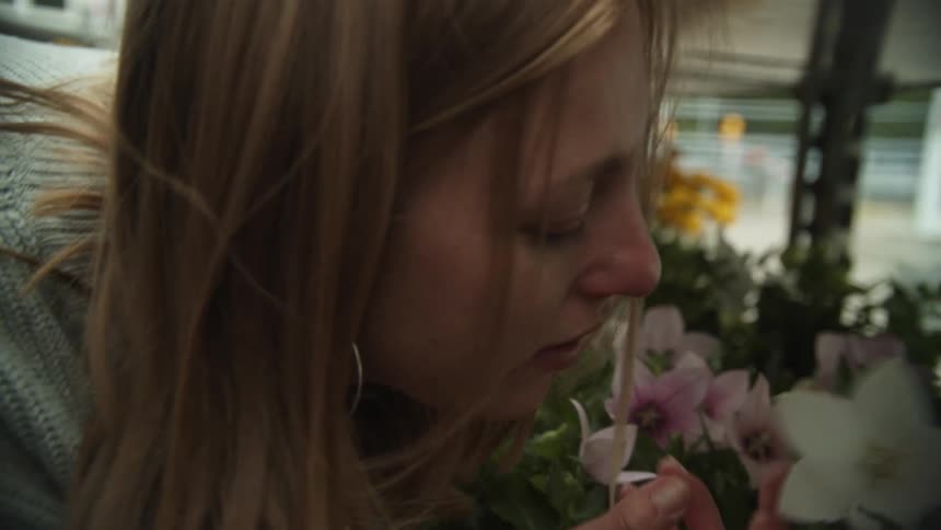 A woman and a girl smelling a flower on shelves with plants