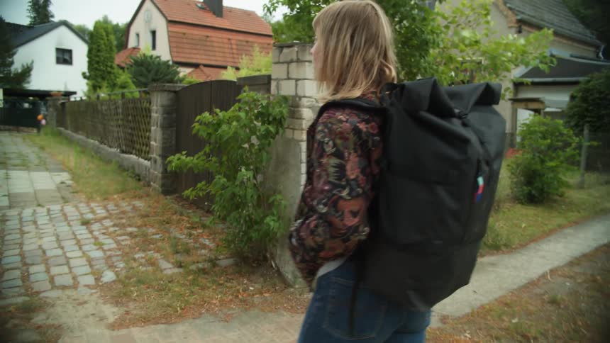 Young woman carrying a backpack walking on the calm streets of the neighborhood