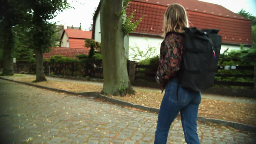 A woman with a backpack on walking down a path