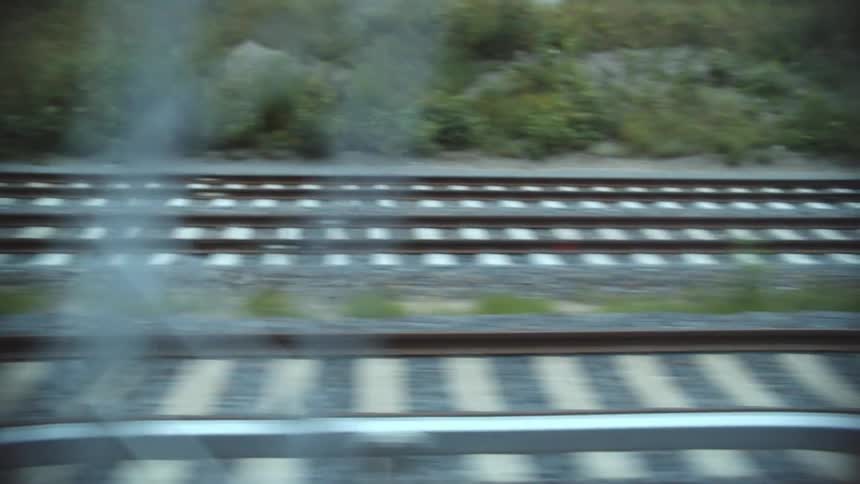 Train tracks filmed from a moving train before entering a tunnel