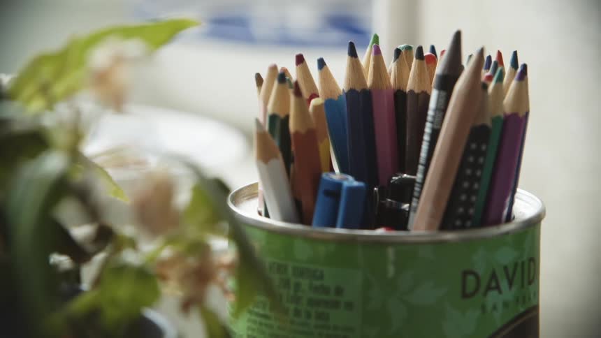 A can being used to hold a variety of colored pencils