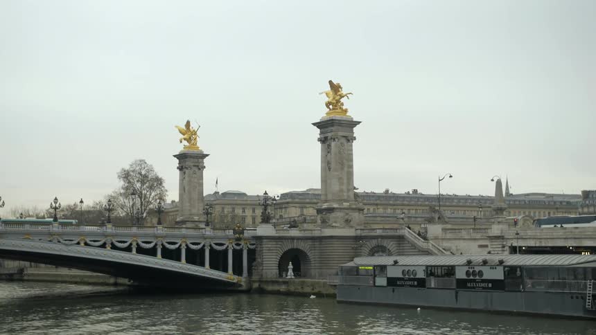 Gold statues sit atop stone pillars near a bridge