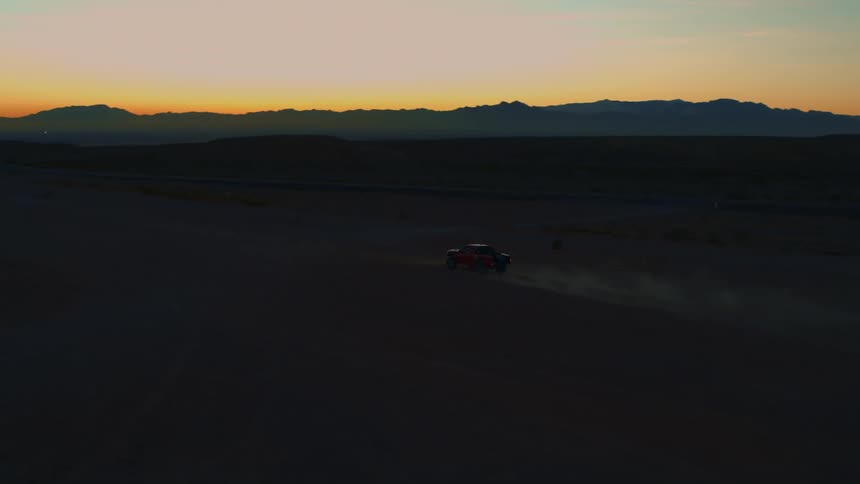 Tight -> Wide backlit tracking shot of Baja truck in desert
