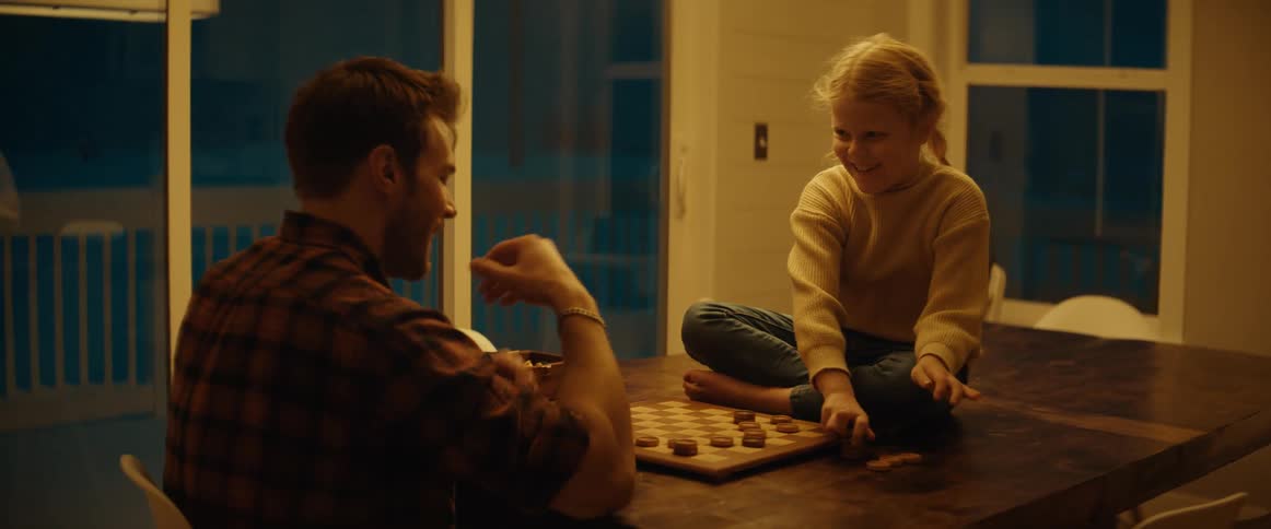 A father and young daughter playing checkers at a dining table