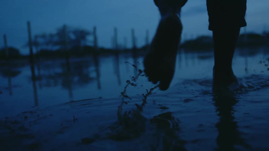 A man walks through a flooded rural area