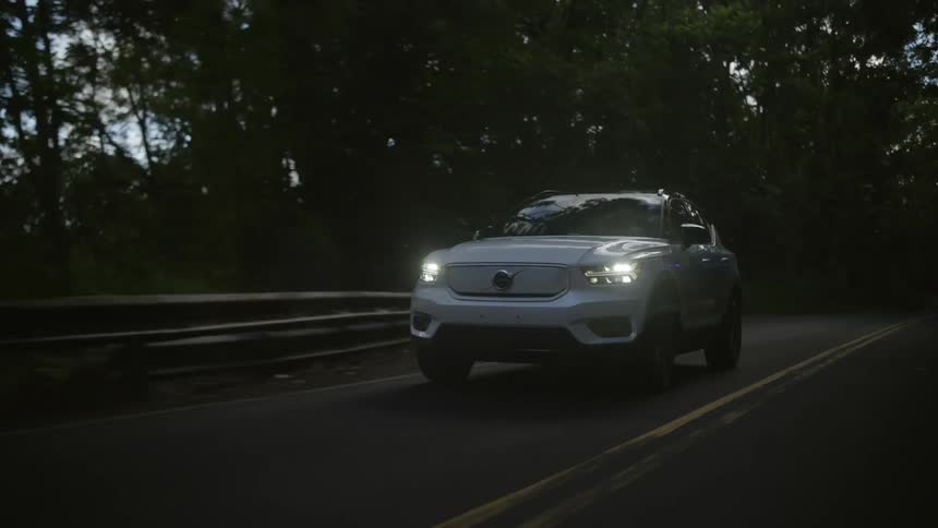 A vehicle drives down a tree lined highway