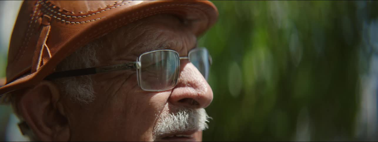 Close up of the face of an elderly man wearing a leather hat outdoors