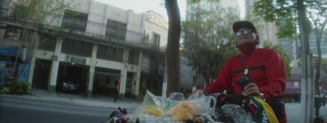 Man pushes full cart along side of busy street