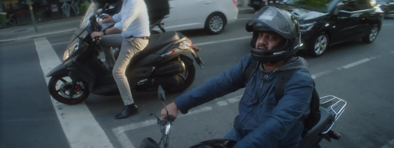 Motorcycle rider stops in the traffic and looks up with a curious expression