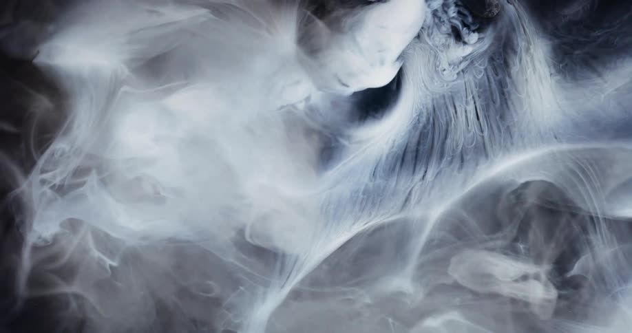 Light shines on wisps of smoke as it spreads and moves across the darkness