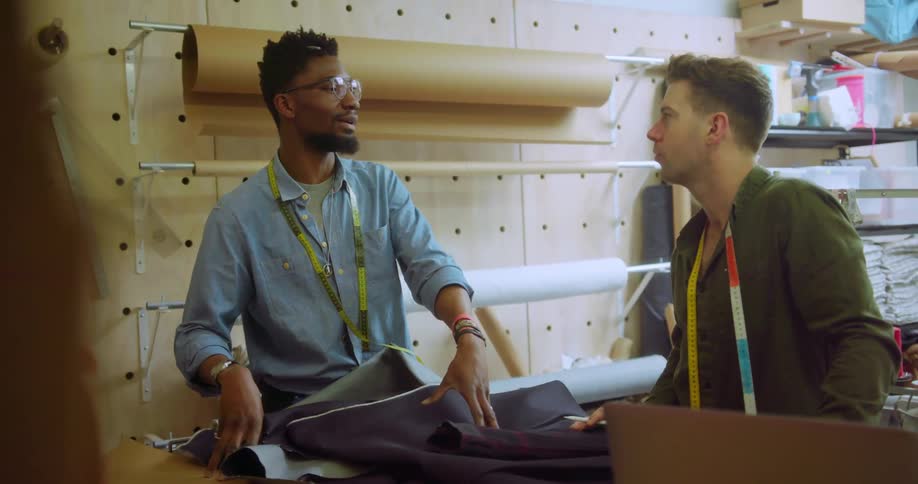 Two men talk while working with fabric