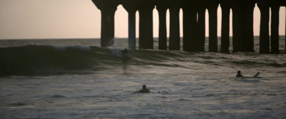 A wave rolls over surfers
