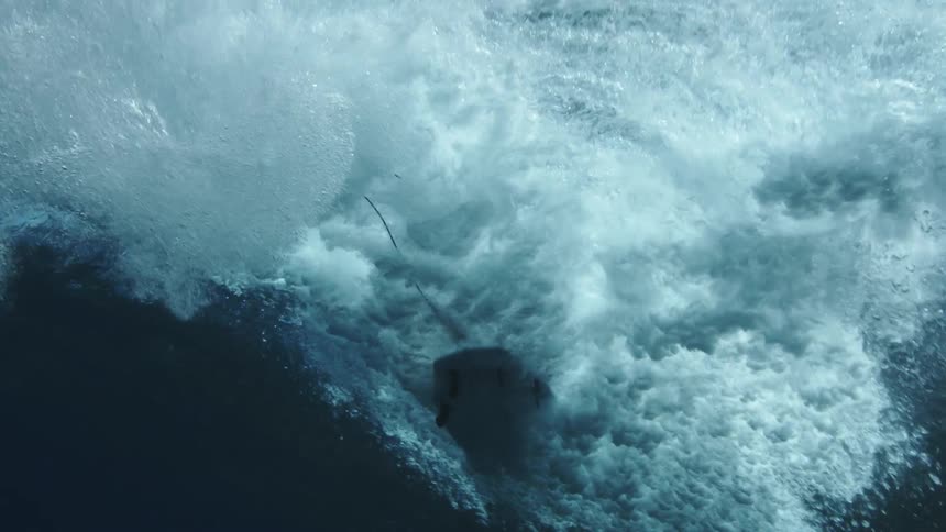 Underwater view looking up as a surfer rides a wave as it rolls overhead