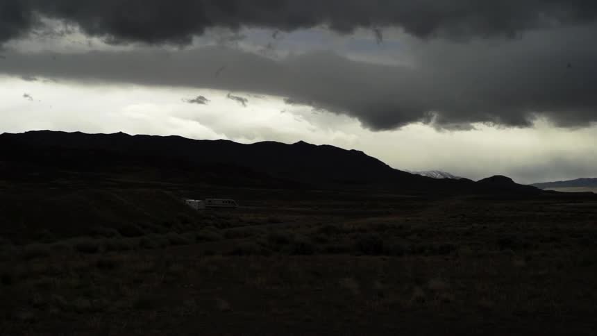 A hilly area is dark with heavy clouds above