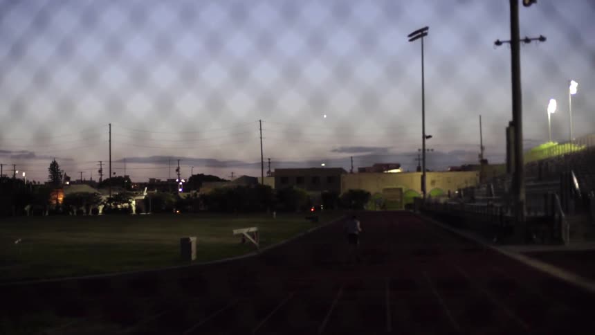 A man jogging along a track at an athletic field