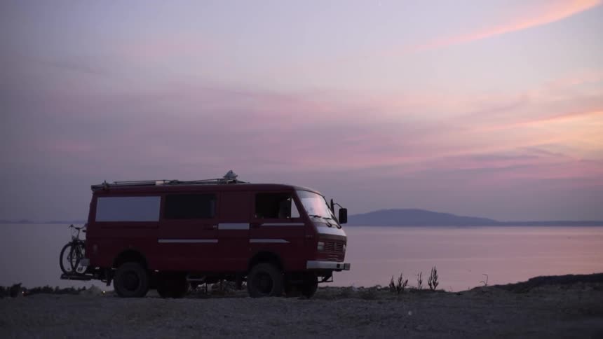 A van parked at the beach during sunset