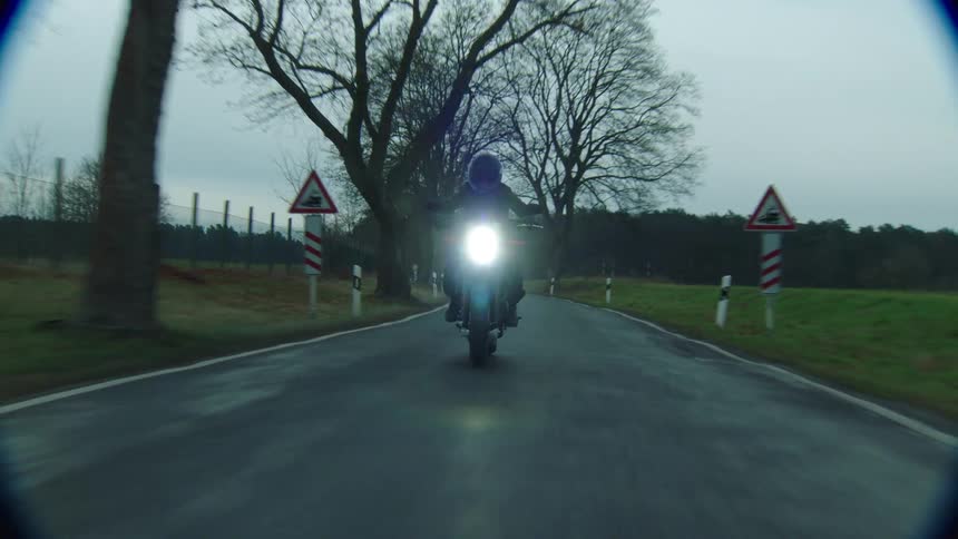 A person drives a motorcycle down a road