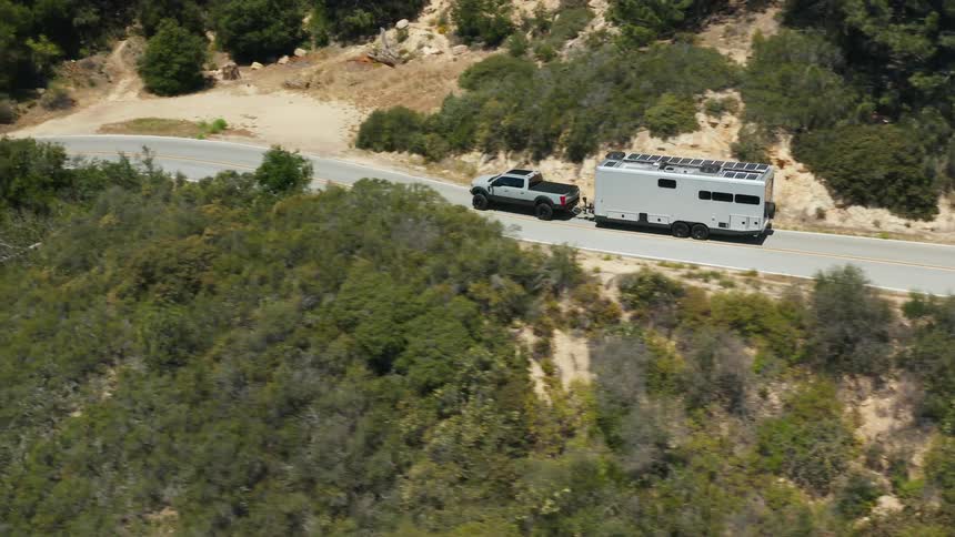 An aerial view of a truck hauling a trailer down a road