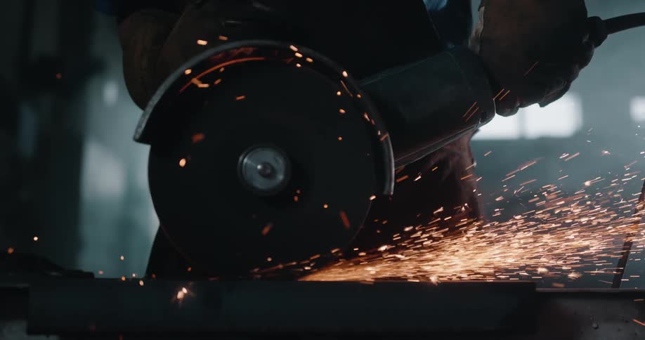 Sparks fly as a worker cuts a piece of metal using a power tool in the warehouse