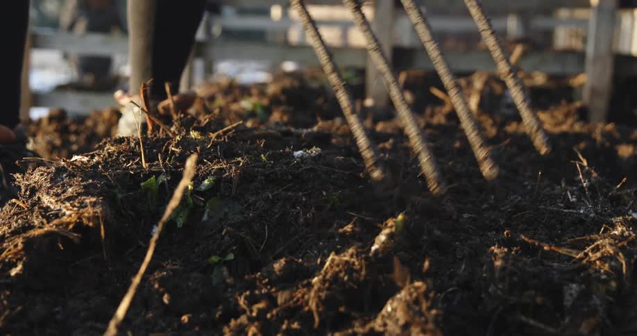 A person is moving mulch with a pitchfork