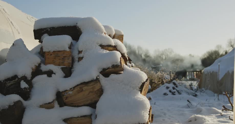 Logs having snow sitting while smoke moves in the background