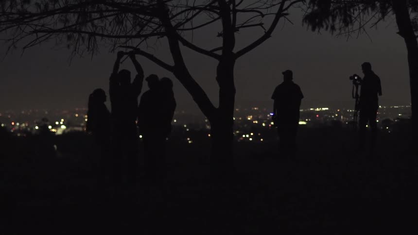 A group of people on a hill under a tree