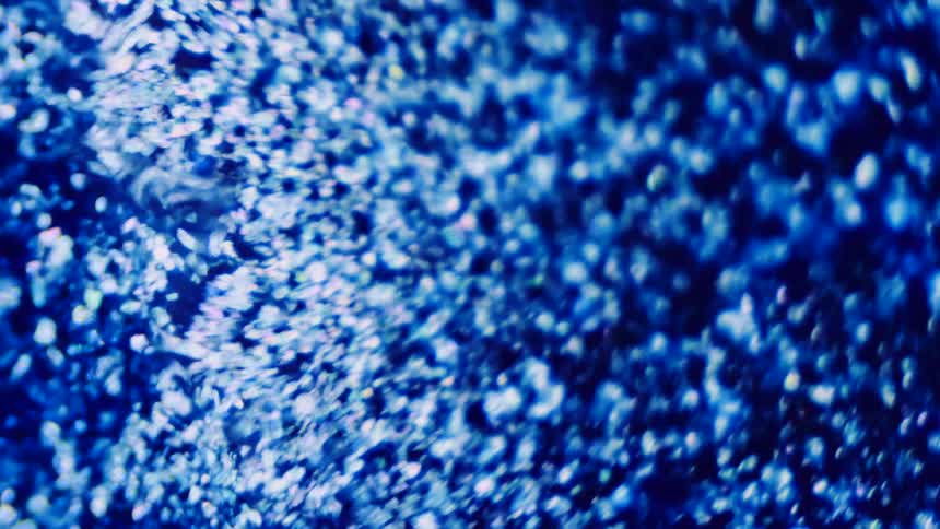 Blue particles floating on liquid cluster together