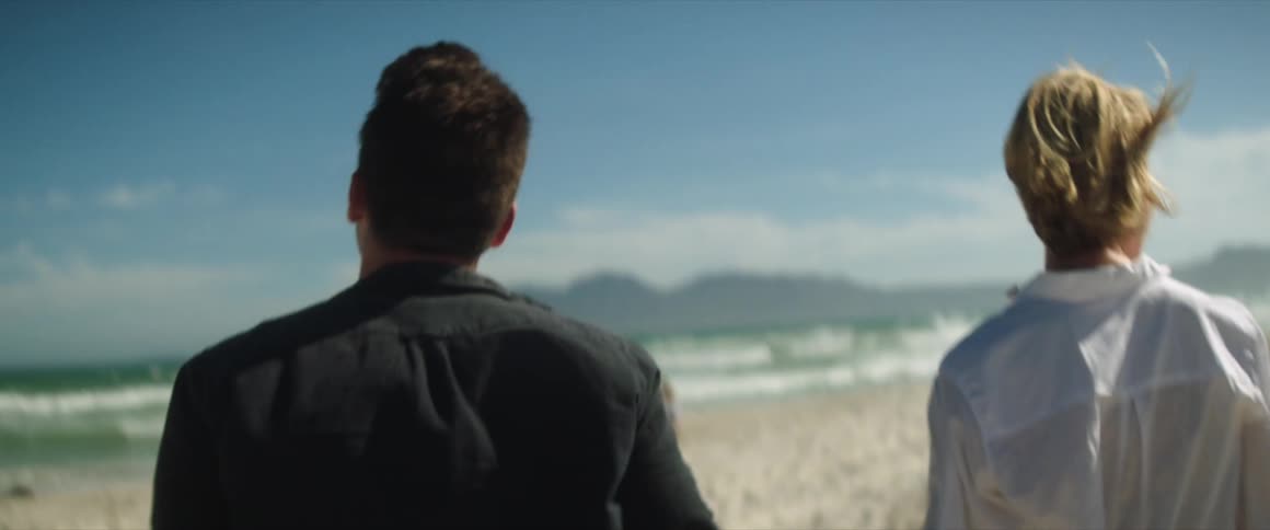 Two people walking on a beach holding hands
