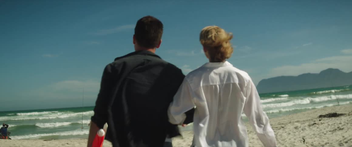 A mother and father walk on the beach towards their child