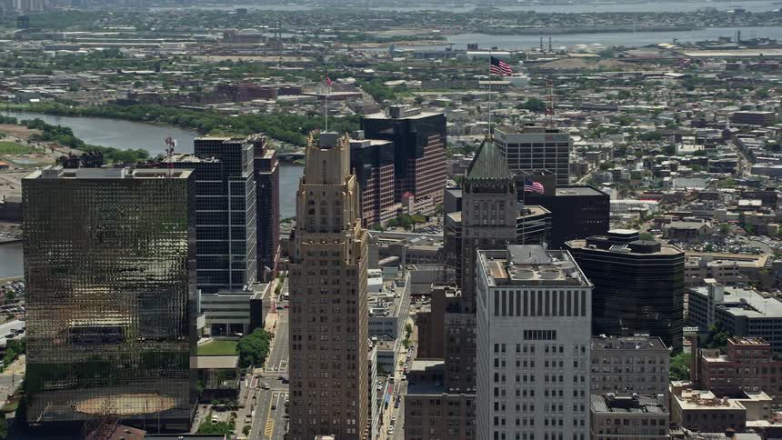 An aerial video clip capturing American flags atop skyscrapers in the bustling downtown area of Newark New Jersey on a sunny day
