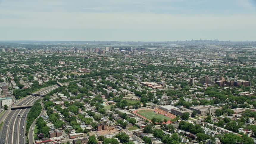 Aerial view of suburban homes near I-78 freeway approaching Downtown Newark New Jersey on a sunny day