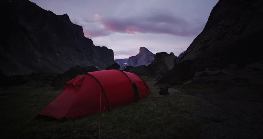 Slow tilt up revealing a red tent and Mount Thor on Baffin Island at this dream campsite