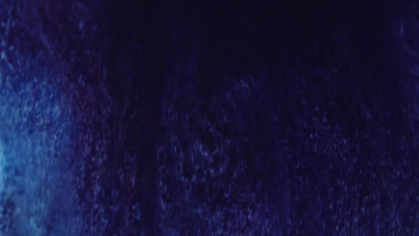 A dark purple and blue textured substance is flowing as the particles inside are moving down