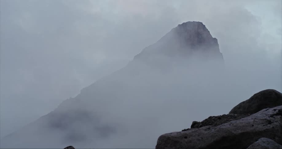 Clouds and fog swirl around the bast of Mount Thor on Baffin Island