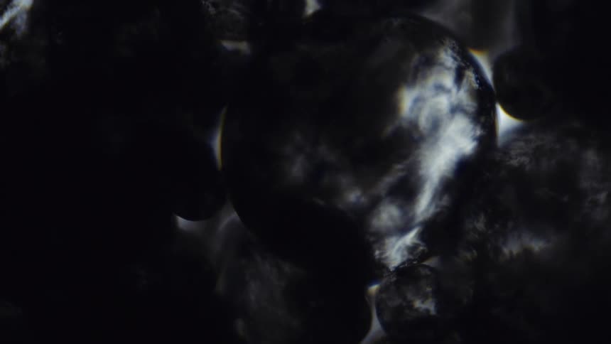 Abstract shapes and textures come into focus in a smokey haze in the darkness
