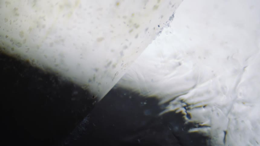 Liquid with particles ripples from top left corner to bottom right