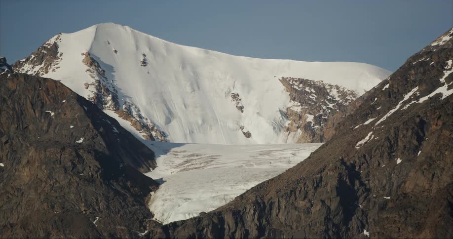 A massive but retreating glacier melts underneath a towering granite peak