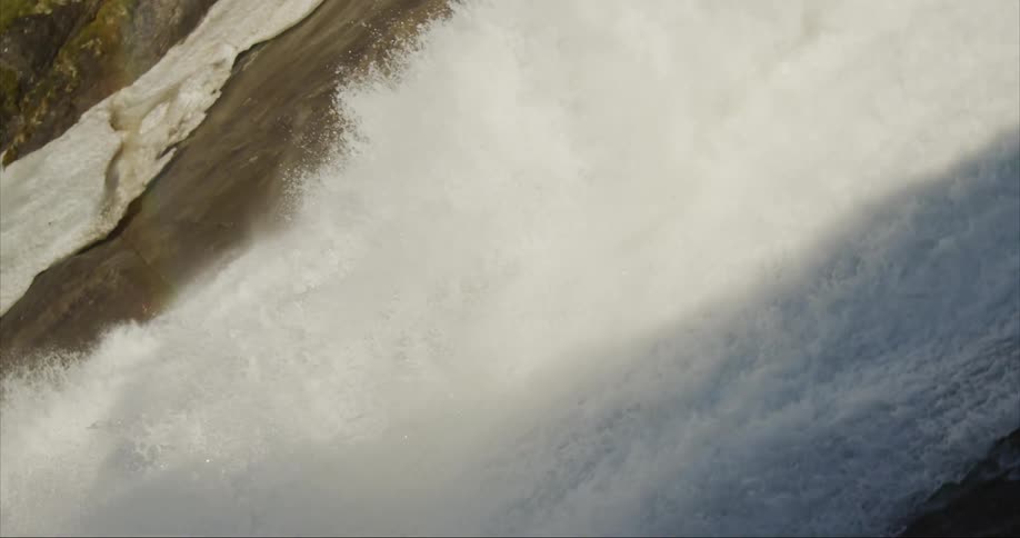 Creative twisting footage of the strong waterfall in the mountains at morning in the alpine