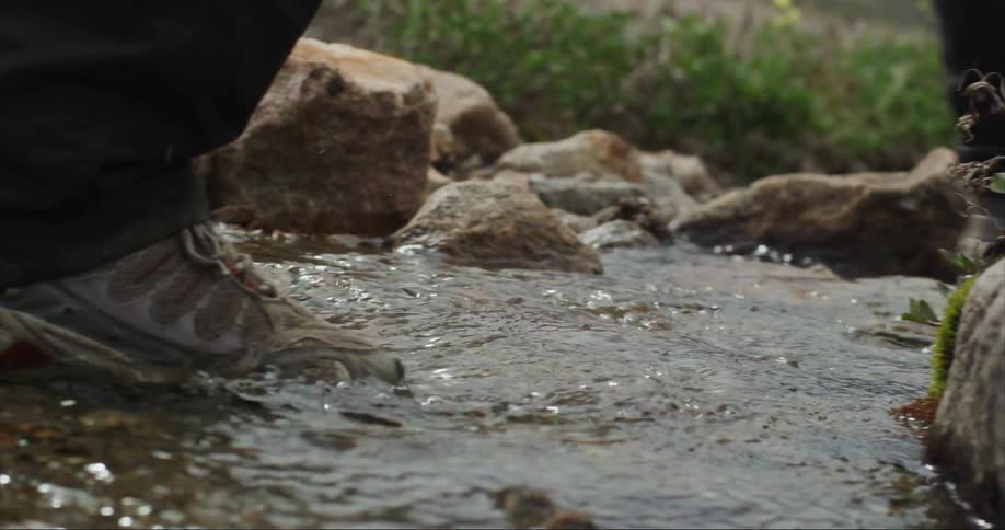 Trekking shoes splash through a side creek as the hiker move towards basecamp