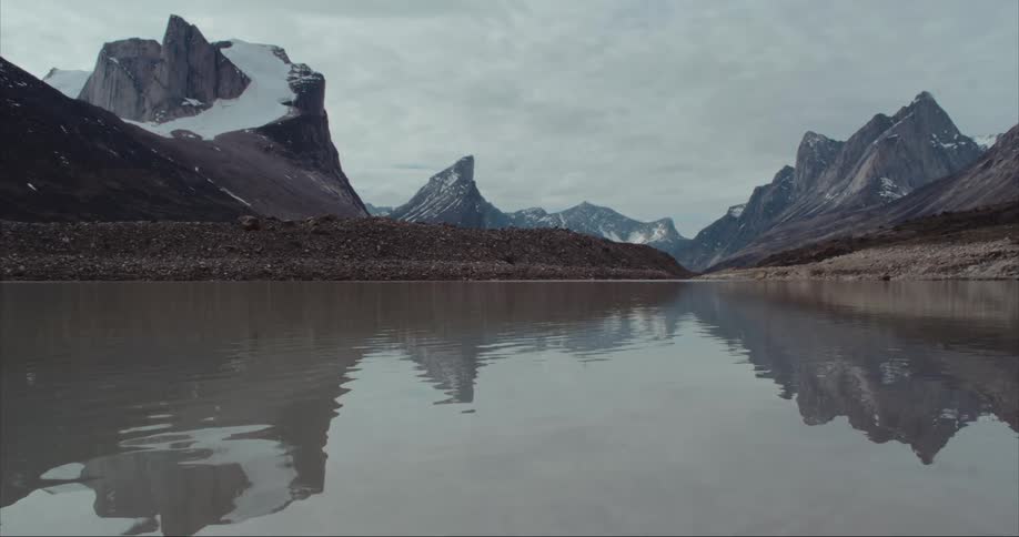 Landscape of a glacier moraine lake with massive glaciers, Mount Thor and other towering granite mountain peaks