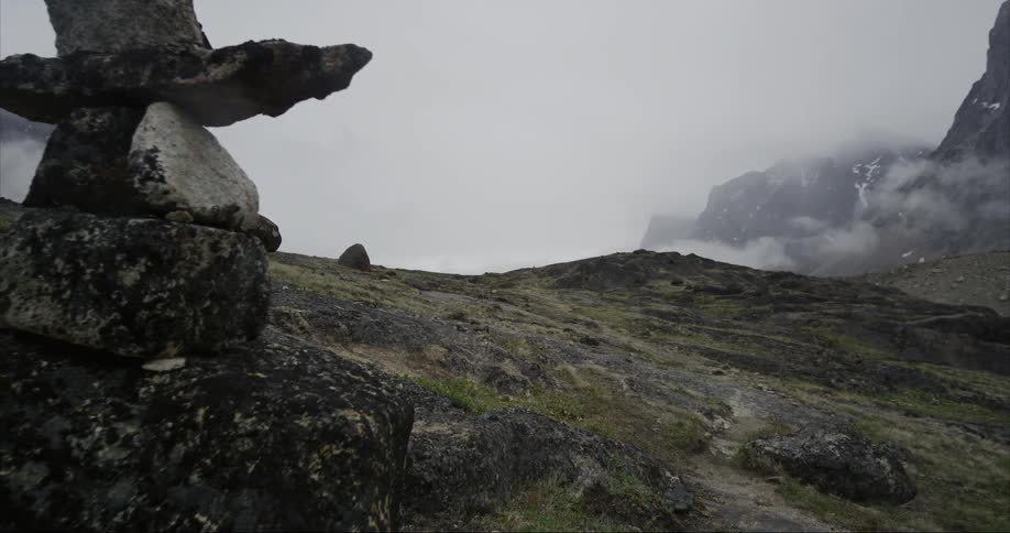 Walking around Inukshuk trail sculptures made with balancing rocks on the mountains under white clouds