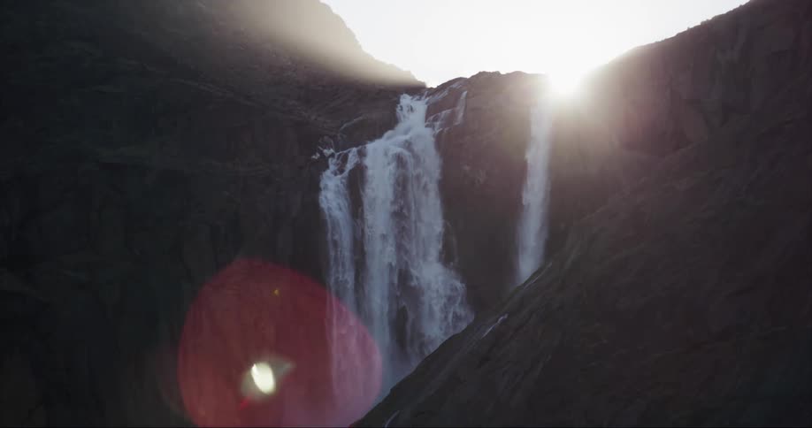 Landscape of massive waterfall cascading down cliff face at sunset