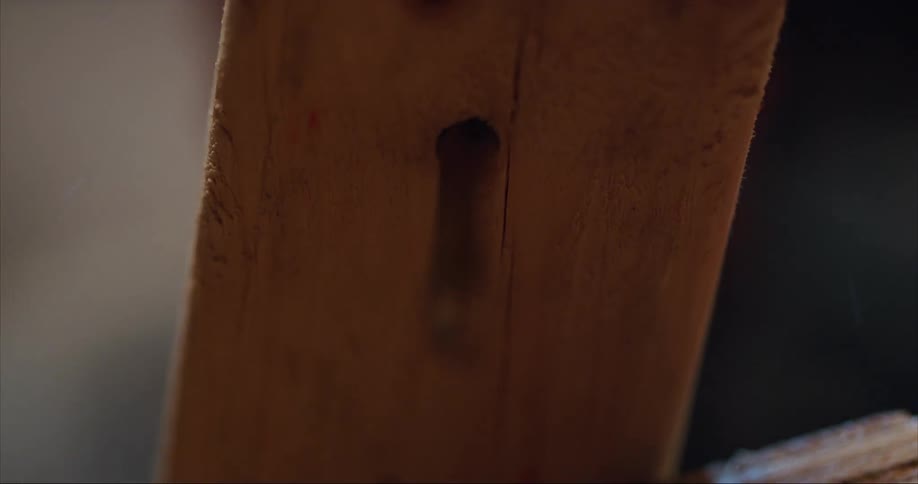 Person drills a hole in wood while building their sea kayak
